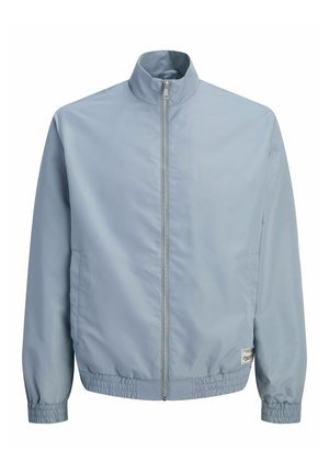 Veste zippée bleu clair avec col montant, poignets et ourlet élastiques, et deux poches latérales, présentée sur fond blanc.