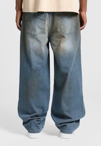 Lyseblå oversized denim jeans med en falmet finish, der har en lige benpasform, baglommer og en opsmøget kant.