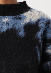 Zwarte en blauwe gebreide trui met wolkachtige patronen, voorzien van een hoge kraag en zachte, geweven stof die op wol lijkt.