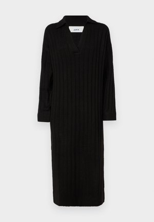 Črna rebrasta pletena obleka z V-izrezom in ovratnikom, dolgimi rokavi in dolžino do kolen. Preprost dizajn z teksturirano površino.