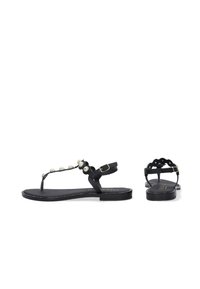 Sorte flade sandaler med T-stroppedesign, dekorative runde detaljer og en justerbar ankelrem med guldfarvet hardware.