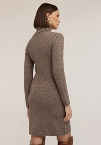 Strick-Turtleneck-Kleid in brauner Farbe, figurbetontes Design und lange Ärmel, mit einer weichen Textur und gerippten Akzenten am Kragen und Saum.