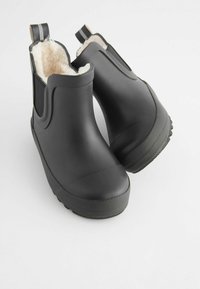 Bottines en caoutchouc noires avec une semelle à texture antidérapante, dotées d'une doublure en fausse fourrure douce et de panneaux latéraux élastiques pour un enfilage facile.