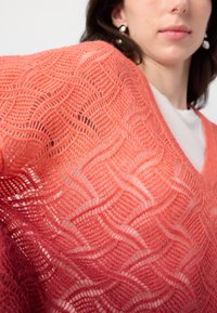 Cardigan en tricot en corail dégradé avec un motif en vagues. Texture légère, design col en V, et légèrement transparent, mettant en valeur les couches en dessous.