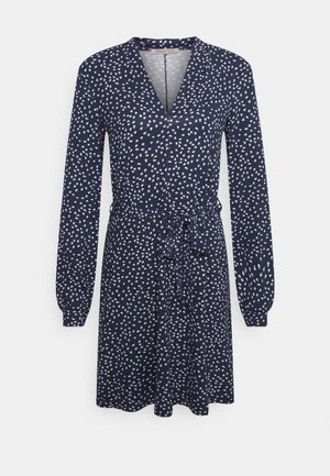 Marineblaues Kleid mit langen Ärmeln und Wickeldesign. Besitzt ein dezentes Punktemuster in Weiß und Hellrosa sowie einen Bindegürtel in der Taille.