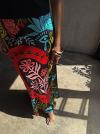 Μάξι φούστα με έντονα λουλουδάτα και γεωμετρικά μοτίβα σε κόκκινο, μπλε, ροζ, πράσινο και μαύρο χρώμα. Συνδυασμένη με μια χρυσή βραχιόλι και παντόφλες.