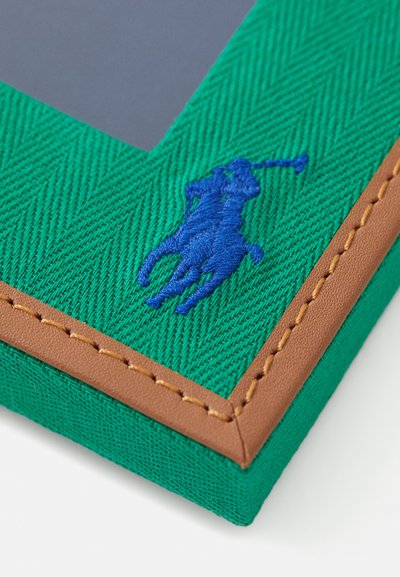 Zeleni herringbone tkaninski okvir za fotografije z modrim vezenim logotipom in rjavim usnjenim poudarkom. Pravokotne oblike s podrobnostmi šivane obrobe.