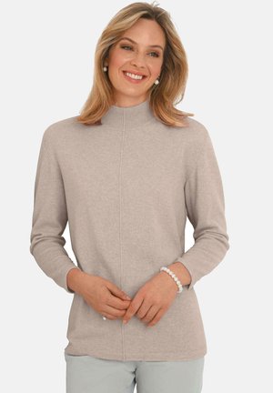 Pull en tricot beige avec col montant, manches longues et coupe droite. Présente une texture lisse et des détails subtils sur le devant.