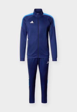 Marineblauw Adidas trainingspak met volledig ritssluiting jack voorzien van lichtblauwe schouderstrepen en bijpassende taps toelopende broek met witte en blauwe zijaccenten.