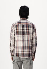 Geruite plaid shirt in beige, blauw en roestkleur; voorzien van knoopmanchetten en een klassieke kraag, gemaakt van zachte stof.