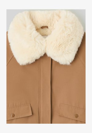 Veste couleur beige avec un col en fausse fourrure crème duveteuse, dotée de deux poches avant et d'une texture de tissu lisse. La fermeture à l'avant n'est pas visible.