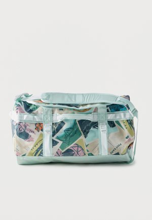 Borsone con manici e base verde menta pastello, caratterizzato da una stampa astratta multicolore che richiama cartoline e disegni.