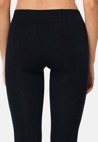 Leggings neri realizzati in materiale morbido ed elastico. Presentano un'alta vita e un design semplice e liscio, senza motivi o accenti.
