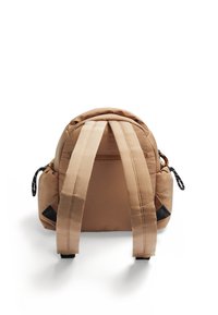 Sac à dos rembourré marron avec deux bretelles épaisses, poches latérales et une fermeture éclair sur le dessus. Présente une forme arrondie et des accents noirs contrastants.