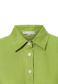 Green linen shirt with a pointed collar, six buttons, and small buttonholes. Label reads "Marie Lund, Copenhagen, 36." Textured fabric.