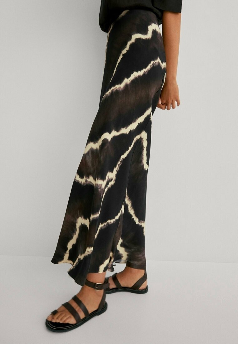 Long black and beige tie-dye skirt with a flared design and side slit, paired with black strappy sandals on a neutral background.