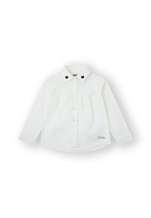 Camisa blanca de manga larga con cuello de punta, que presenta dos acentos en forma de corazón negro, botones frontales y detalle bordado con la palabra "CHic".