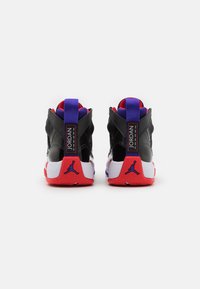 High-top basketball shoes featuring a black upper, purple accents, red sole, and contrasting white midsole with a Nike Air Jordan logo.