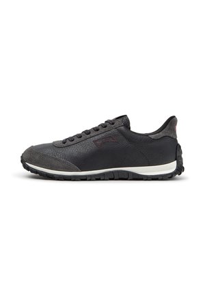 Black low-top casual sneaker with textured leather and suede details, black laces, and a white sole with a rugged black tread.