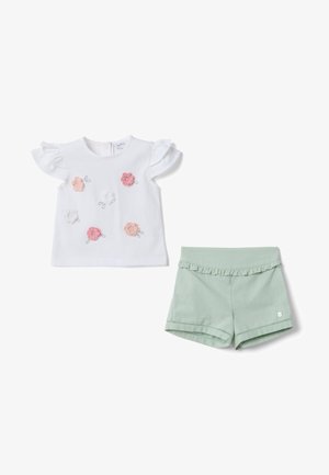 Camiseta blanca de manga corta para niño pequeño con flores bordadas en tonos rosa y melocotón, combinada con pantalones cortos verde claro con volantes, sobre fondo blanco.