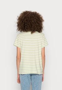 T-shirt de manga curta às riscas em amarelo claro e verde. Material de algodão suave, corte descontraído, com um acabamento reto e design na parte de trás do pescoço.