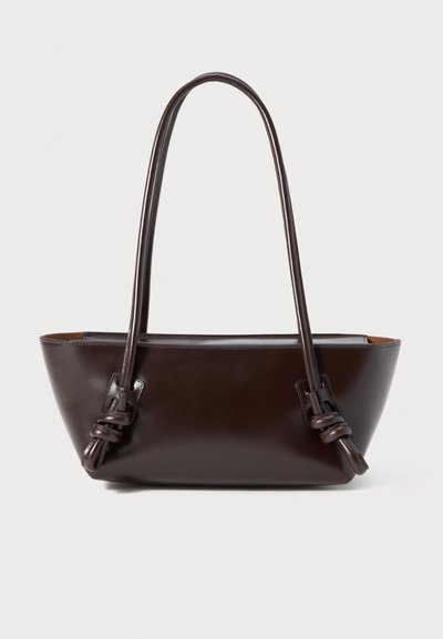 Bolso de cuero marrón oscuro con dos asas anudadas y un cuerpo en forma de trapecio.