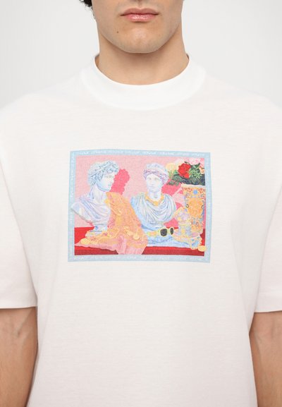 Witte T-shirt met korte mouwen, met een kleurrafische afbeelding van klassieke busten en een bloemenarrangement, omrand met een blauwe rand en tekst.