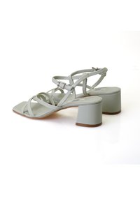 Mintgrüne High-Heelsandalen mit quadratischer Zehenpartie, die mehrere Riemen und einen Blockabsatz aufweisen. Glatte Textur und verstellbarer Knöchelriemen.