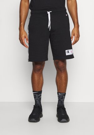 Czarne bawełniane szorty z elastycznym pasem i białym sznurkiem, z białymi paskami po bokach, z naszywką z logo na prawej nodze.