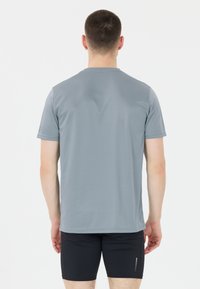 Harmaa lyhythihainen urheilupaita kevyestä materiaalista, sileä pinnaltaan, pyöreä kaula-aukko. Yhdistetty mustiin shortsit, joissa on pieni heijastava yksityiskohta.