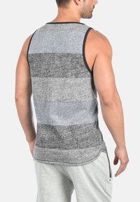Graues Tanktop mit horizontalen Streifen in verschiedenen Grautönen, schwarzem Saum am Hals und einer lockeren Passform mit abgerundetem Saum.
