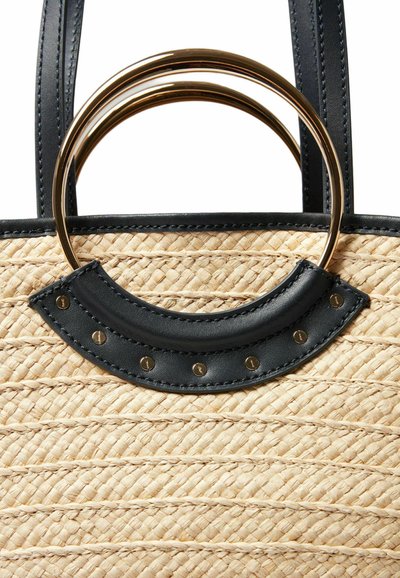 Borsa a rete in paglia con dettagli in pelle nera e hardware dorato. Presenta due anelli metallici circolari e un motivo intrecciato testurizzato sul corpo principale.
