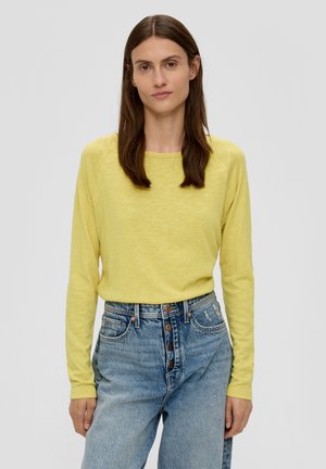 Geel, lange mouwen t-shirt met een ronde halslijn, gemaakt van een lichtgewicht stof, gecombineerd met hoge blauwe denim jeans met vijf knopen.
