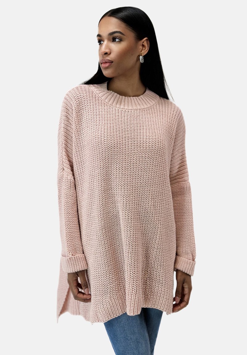 Maglione lavorato a maglia rosa chiaro con scollatura rotonda a coste, maniche lunghe e spacchi laterali. Tessuto testurizzato con una vestibilità ampia.