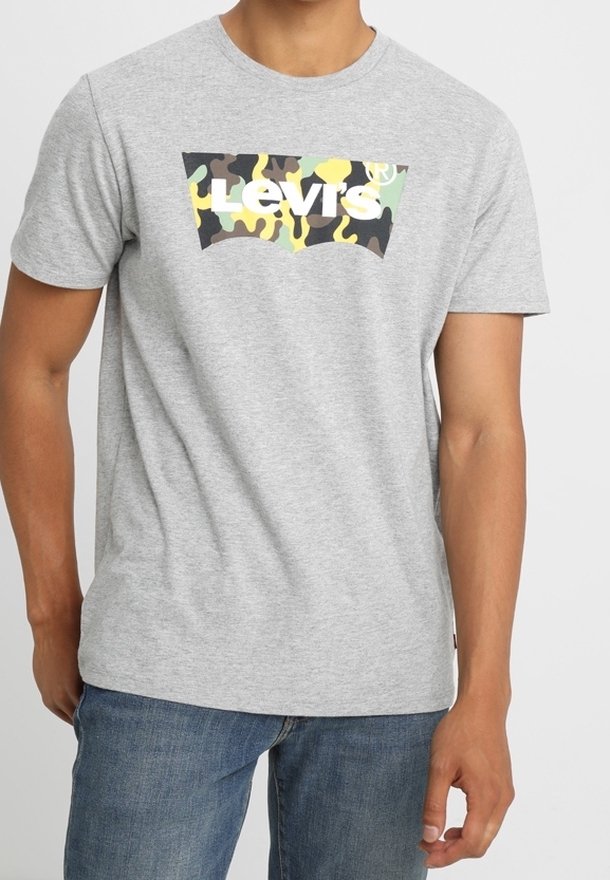 T-shirt en coton gris avec un logo Levi's en camouflage sur la poitrine. Coupe régulière avec des manches courtes et un col rond. Porté avec un jean bleu.