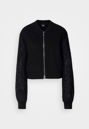 Cropped black knitted cardigan with a solid body, ribbed neckline, and textured knit sleeves. Features a front zip closure and elastic cuffs.