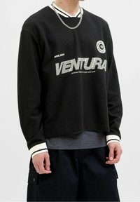 Felpa nera a maniche lunghe con texture a coste, colletto a righe bianche a contrasto, grafica audace "VENTURA" e vestibilità rilassata.