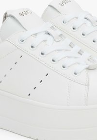 Witte leren sneakers met een gladde afwerking, voorzien van geperforeerde details, platte witte veters en een gestructureerde rubberen zool.