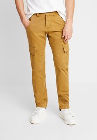 Beige cargo hlače iz mešanice bombaža. Značilnosti vključujejo stranske žepe, raven kroj in lahko, gladko teksturo.