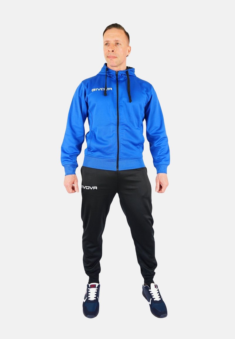 Modra zip-up kapuca s črnimi hlačami; nudi udoben fit, elastične manšete in belo oznako na prsih ter hlačah.