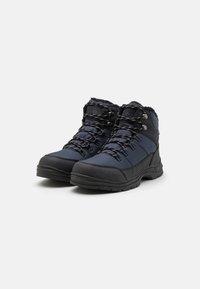 Meripakan sepatu hiking navy dengan bagian atas kain bertekstur, sol karet hitam, dan bagian depan yang bisa diikat; dilengkapi dengan pelapis berbulu dan aksen reflektif.