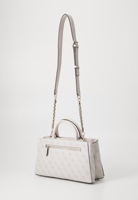 Strukturert håndveske i lys beige materiale med logo mønster. Har en topphåndtak, justerbar stropp og en frontlomme med glidelås. Gullfargede detaljer.