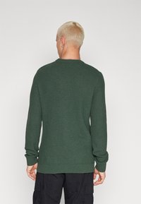 Green knitted sweater with a textured pattern, round neckline, and ribbed cuffs. Suitable for casual wear.