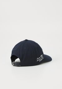 Casquette bleu marine avec une visière courbée, en coton, ornée d'un texte brodé sur le côté et d'une sangle à boucle ajustable à l'arrière.