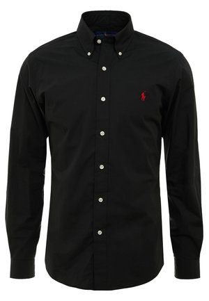 Schwarzes Hemd mit langen Ärmeln und Knopfleiste, Knopfkragen und kleinem roten Logo, das auf der linken Brust gestickt ist.