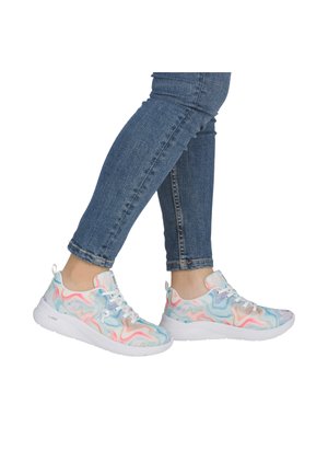 Person wearing blue jeans and white sneakers with pastel multicolor swirl patterns, standing with one foot slightly raised.