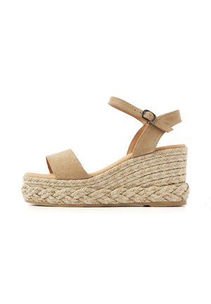 Beige suede wedge sandal with ankle strap and buckle, featuring a braided jute platform sole.