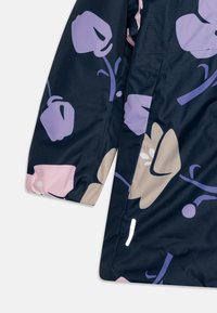 Marineblå jakke i stoff med overdimensjonerte blomsterdesign i lavendel og rosa. Inkluderer en reflekterende detalj på ermene for synlighet.