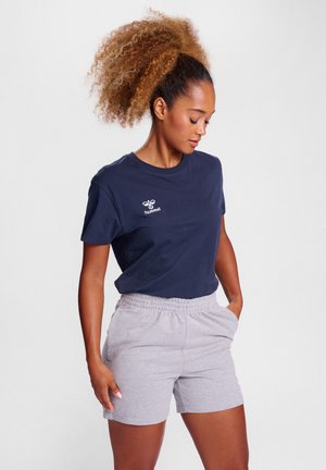 T-shirt marine à manches courtes avec un logo blanc sur la poitrine, associé à un short à taille élastique gris clair. Texture en coton lisse.