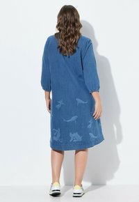Denimmekko, jossa on kolmen neljänneksen hihat, väljä istuvuus ja kalakuviot vaaleammassa sävyssä alaosassa. Sileä pinta ja polvipituus.
